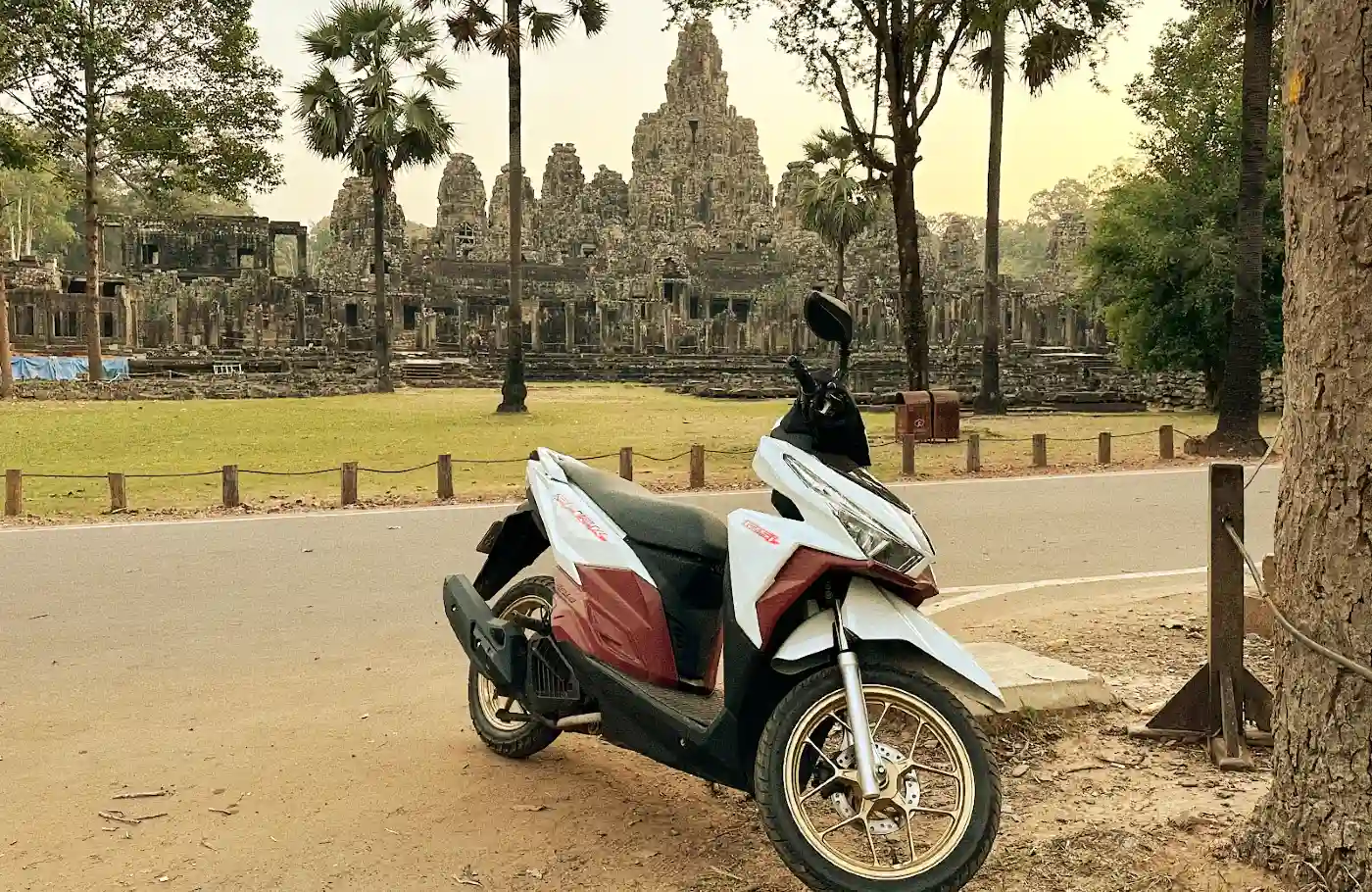 Scooter parked in front of Bayon temple at Angkor with intricate stone architecture
